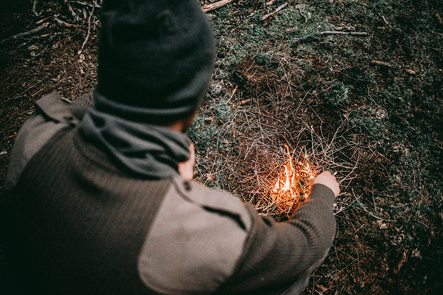 Osoba rozpala ognisko w lesie