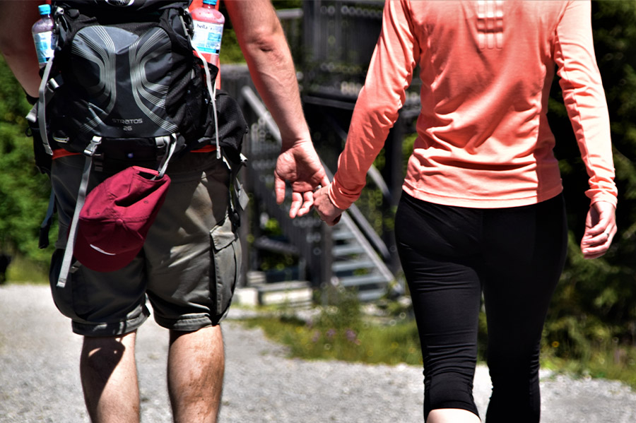 Mężczyzna i kobieta z plecakami trzymają się za ręce