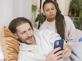 zona za plecami męża niezadowolona patrzy mu w telefon