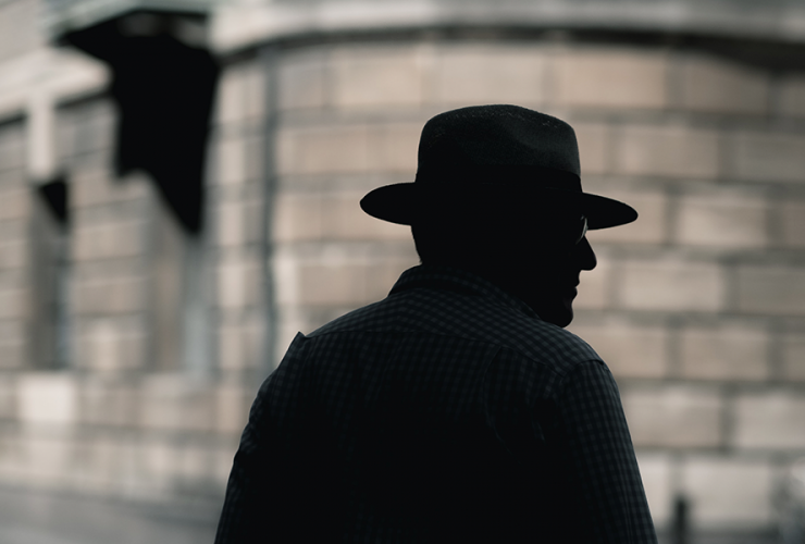 Detektyw w ciemnym kapeluszu stoi na ulicy