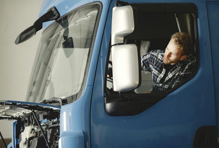 mężczyzna siedzi za kierownicą niebieskiej ciężarówki