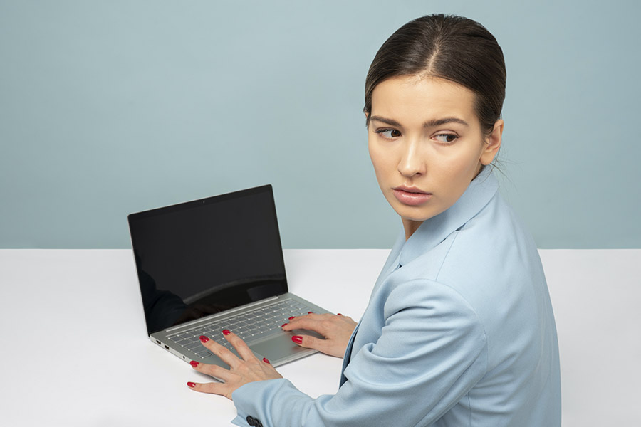 Kobieta siedzi przed laptopem oglądając się za siebie