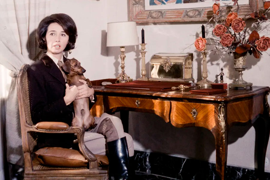 Aline Griffith siedzi na fotelu z psem przy stole