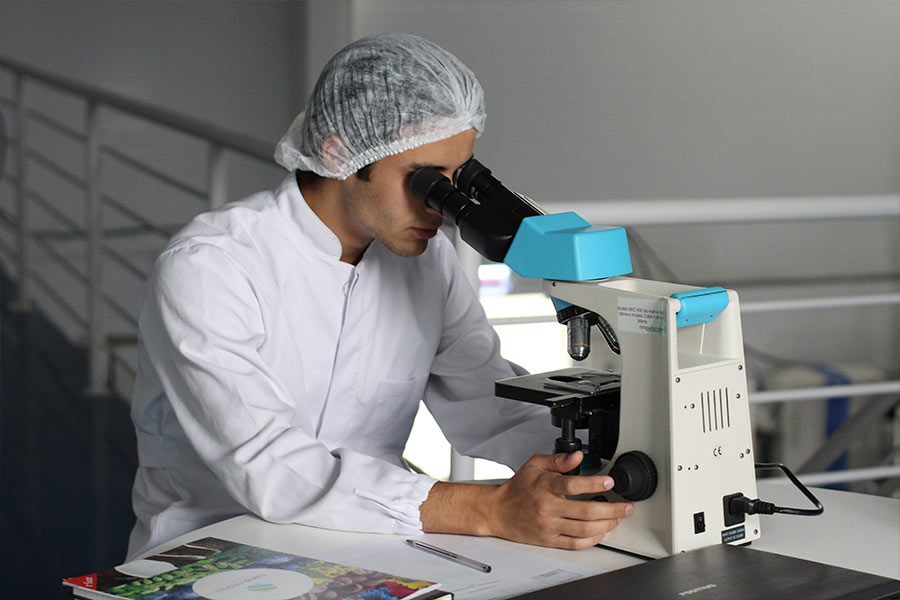 Naukowiec w laboratorium siedzi przy mikroskopie