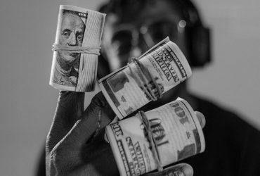 Osoba czarnoskóra trzyma dolary w rękach