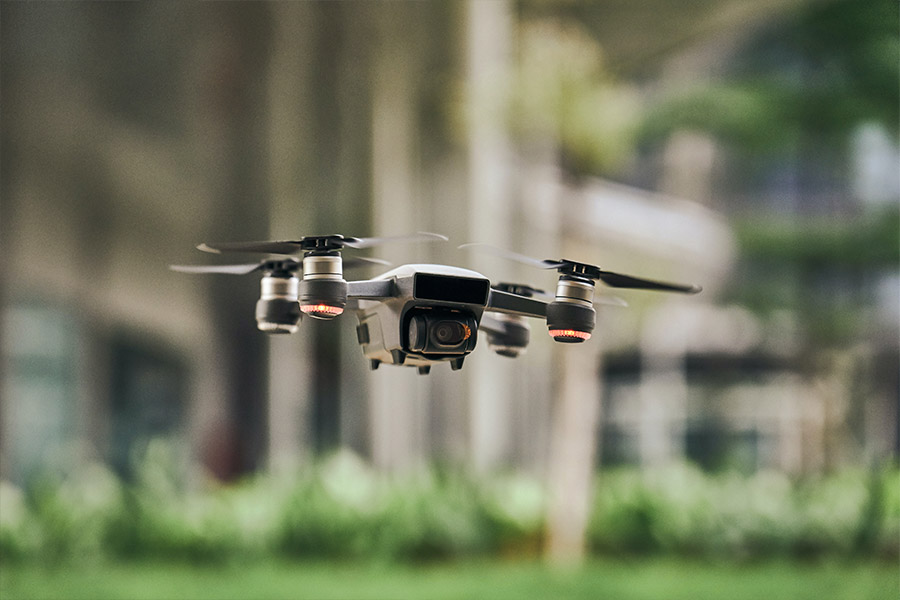 Szary dron leci nad ziemią w lesie