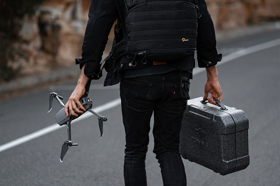 Mężczyzna trzyma drona w jednej i walizkę do drona w drugiej ręce