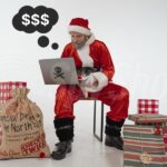 Haker Mikołaj siedzi przy laptopie obok prezenty w workach