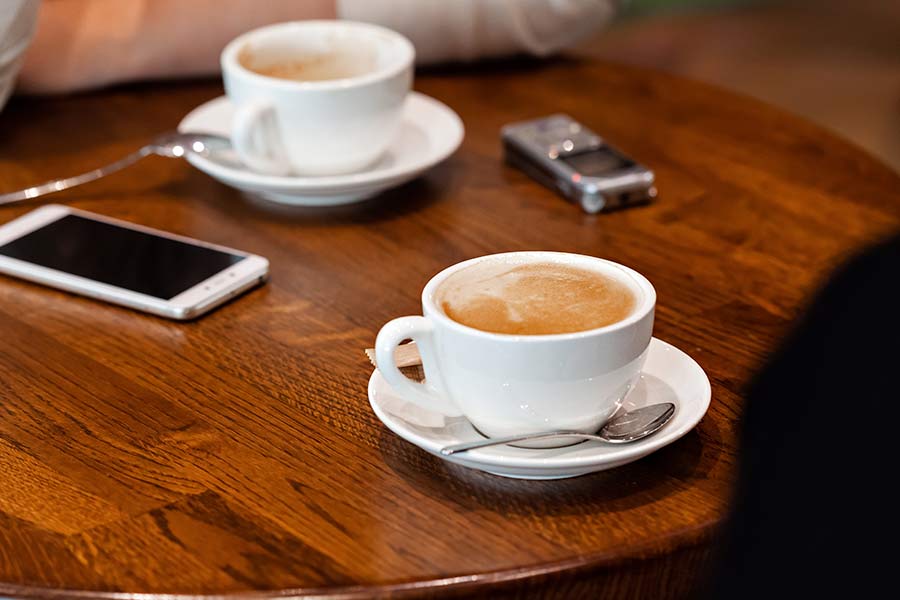 Dyktafon leży na stoliku obok filiżanek z kawą