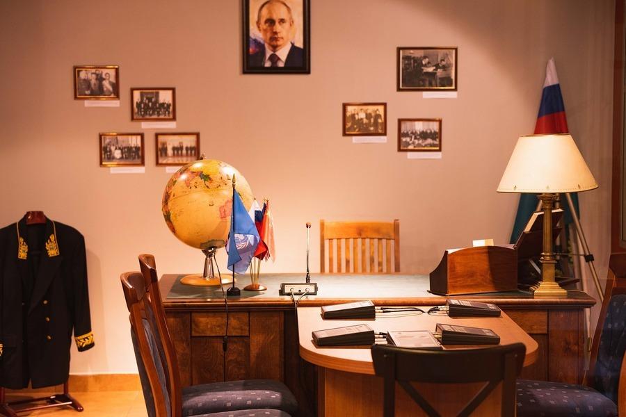 Gabinet służbowy rosyjskiego urzędnika. Na ścianie wisi portret Putina. W rogu pomieszczenia stoi flaga Rosji