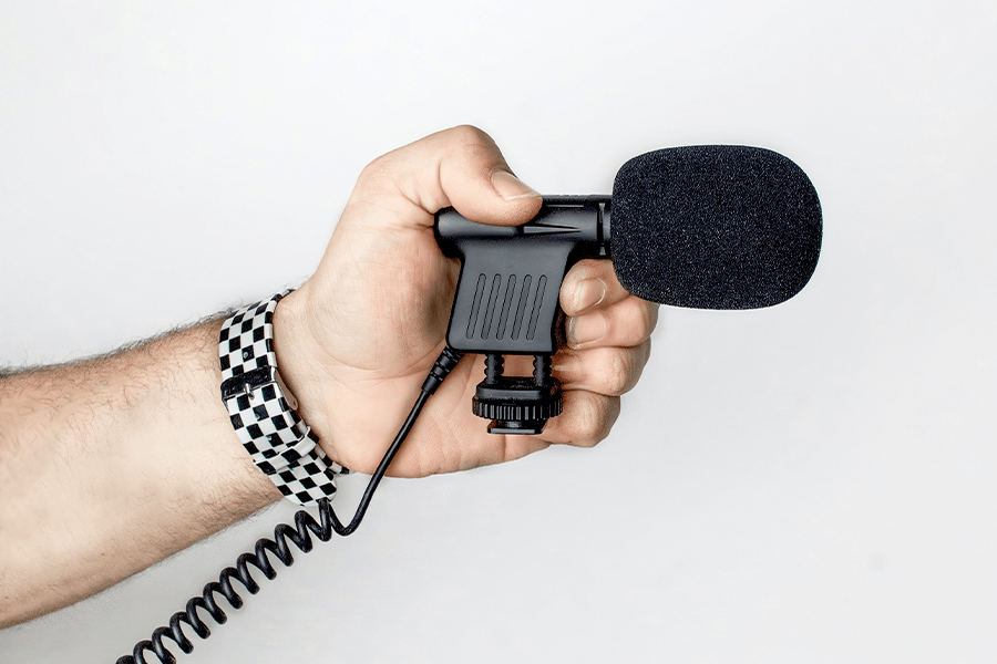Osoba trzyma w ręce czarny mikrofon