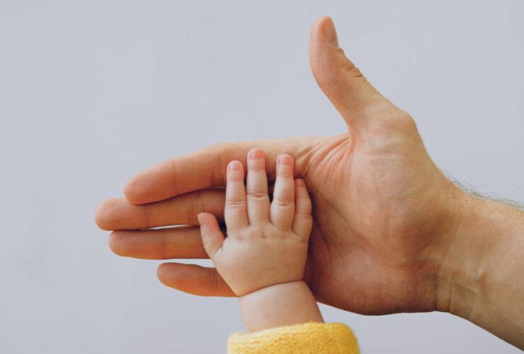 Ręka ojca trzyma małą rękę swojego dziecka
