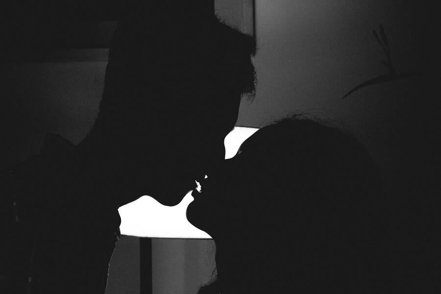 Cień całującej się pary w sypialni, w której zgaszone jest światło