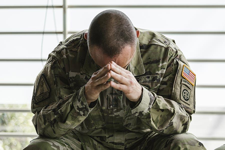 amerykański żołnierz w mundurze moro siedzi składając ręce przy twarzy