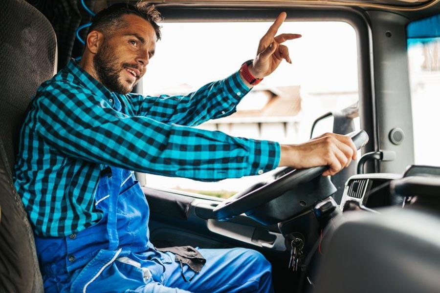 kierowca ciężarówki siedzi w niebieskiej koszulce w kraty za kierownicą