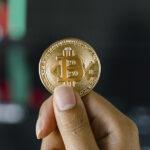 złota moneta bitcoin w rękach osoby
