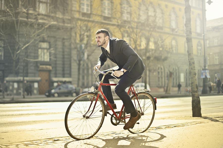 mężczyzna w garniturze jedzie na rowerze przez miasto