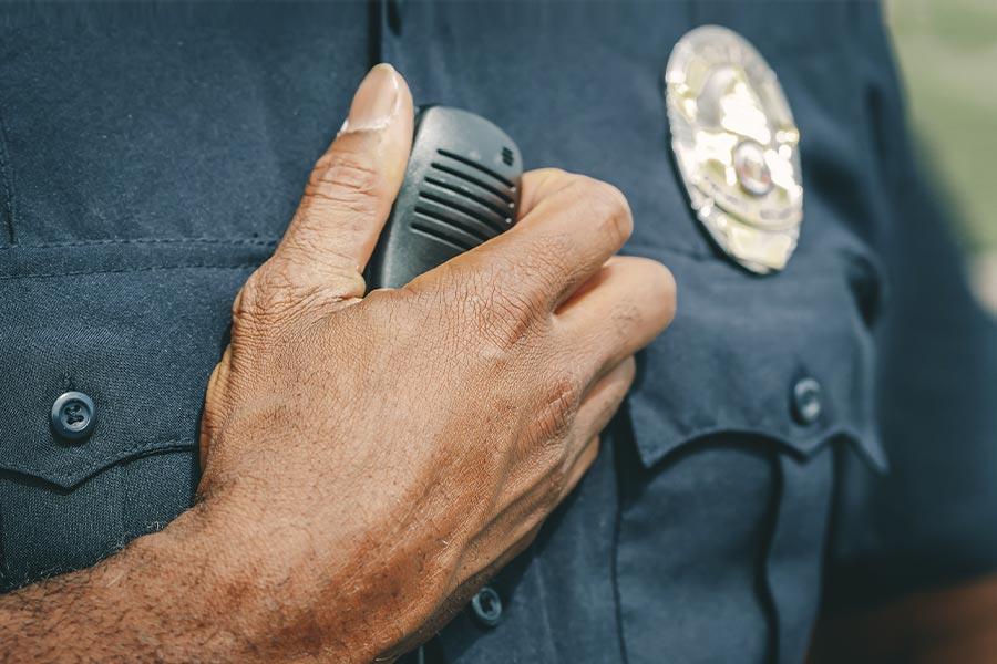 policjant w niebieskim mundurze trzyma któtkofalówkę w ręce