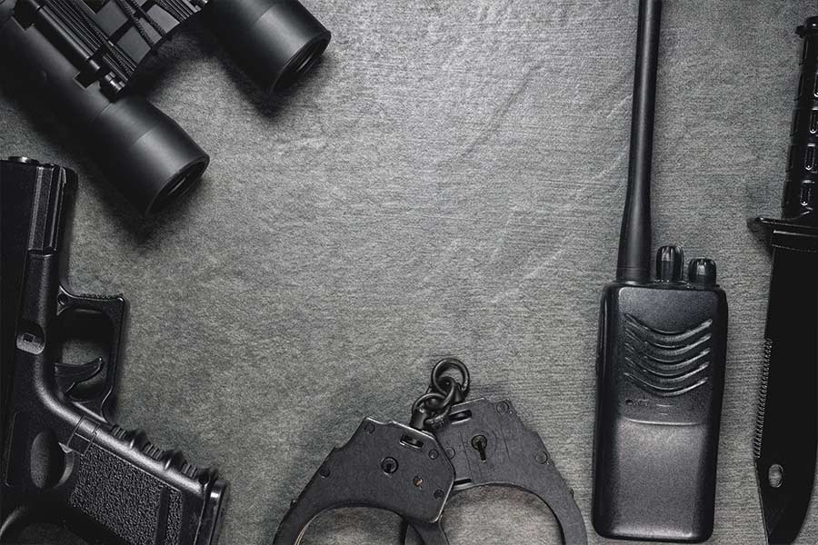 uzbrojenie służby więziennej kajdanki pistolet lornetka leżą na szarym stole