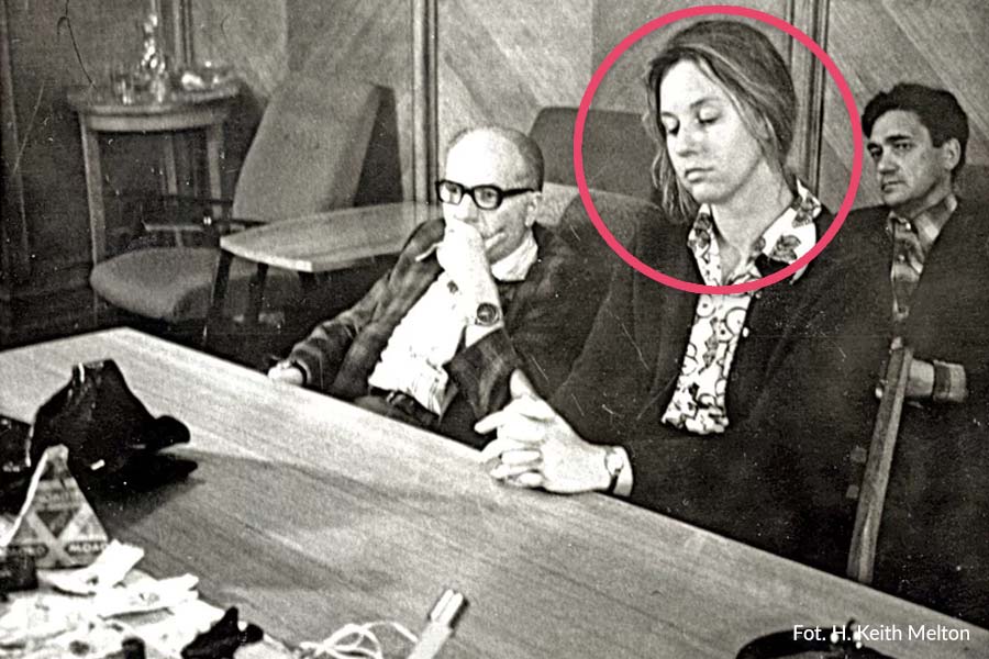 kobieta siedzi obok mężczyzn przy stole patrząc na dół