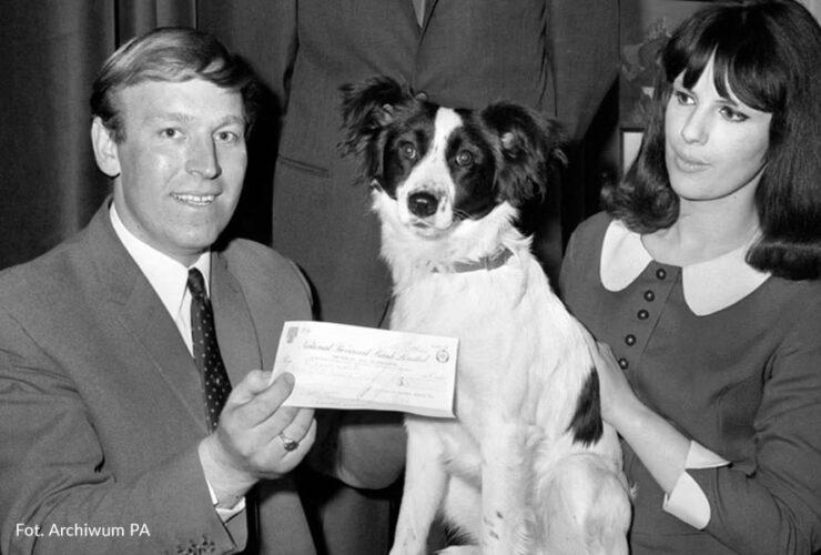 Czarno-białe zdjęcie psa Picklesa z zadowolonymi właścicielami po odbiorze nagrody w postaci czeku za odnalezienie Pucharu Świata