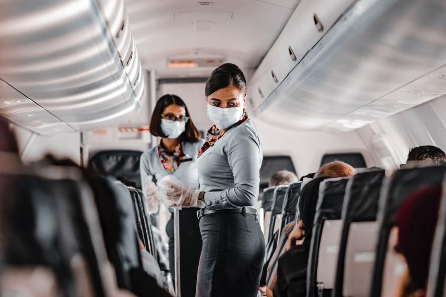 Stewardessy w maseczkach na pokładzie samolotu sprawdzają pasażerów