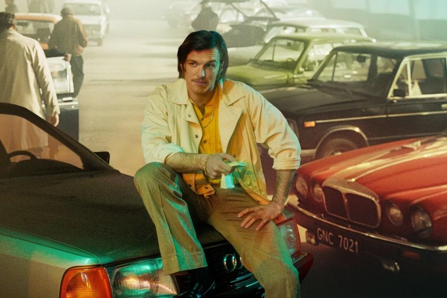 Kadr z filmu "Jak pokochałam gangstera". Tomasz Włosok siedzi na masce samochodu.
