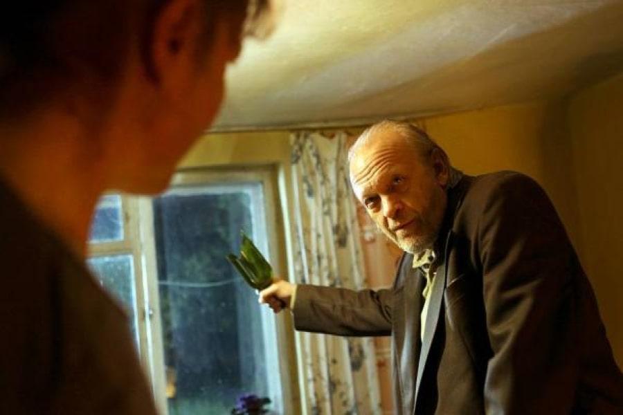 Kadr z filmu "Lincz". Wiesław Komasa trzymający w dłoni ubitą szklaną butelkę.