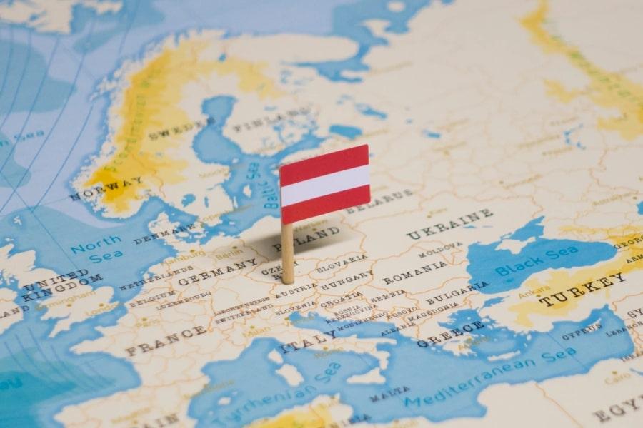 Zdjęcie papierowej mapy Europy. W miejscu Austrii wbita jest mała flaga Austrii.